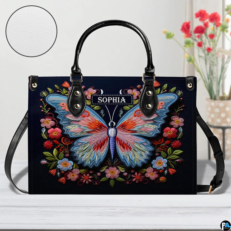 Front perspective of the embroidered butterfly handbag resting on a white tabletop.