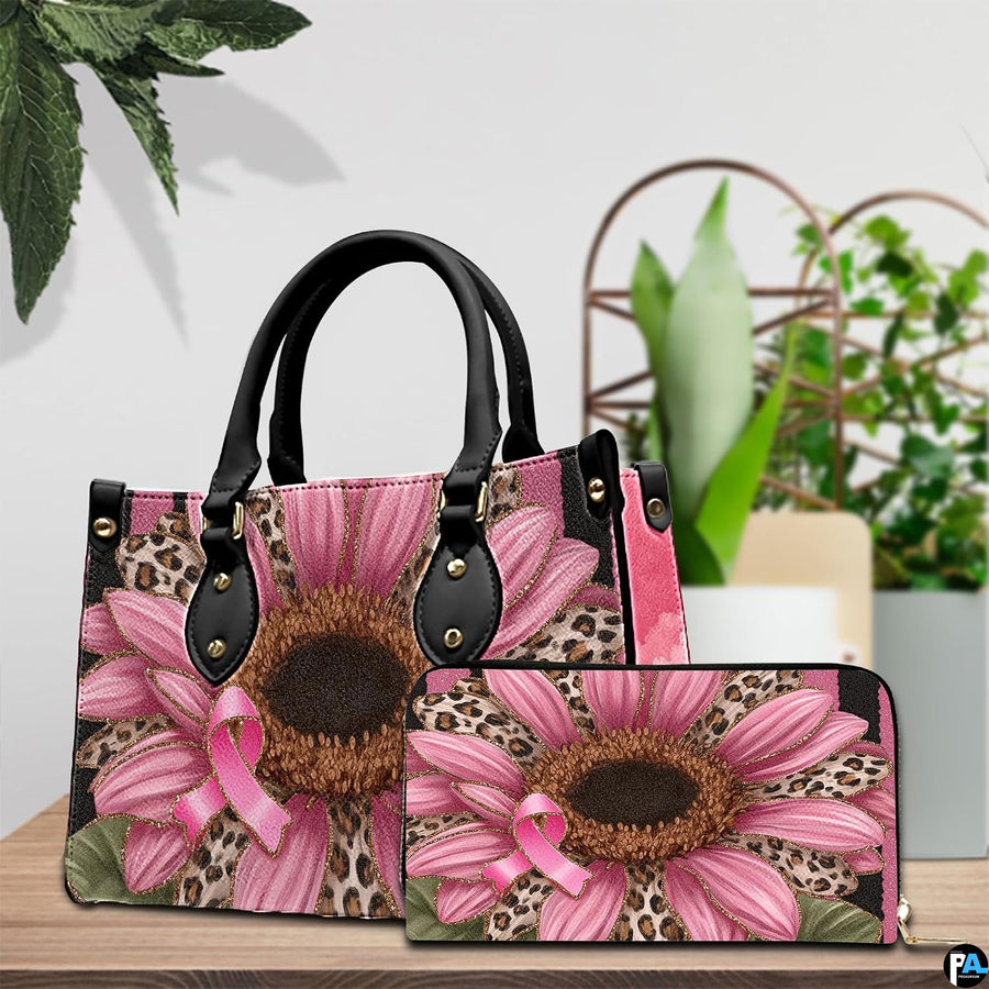 Pink sunflower art accessory and companion item arranged together on timber tabletop near green potted foliage.