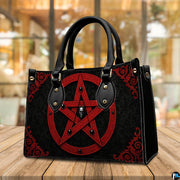 Crimson pentagram handbag displayed on wooden tabletop in front of sunlit cafe window.