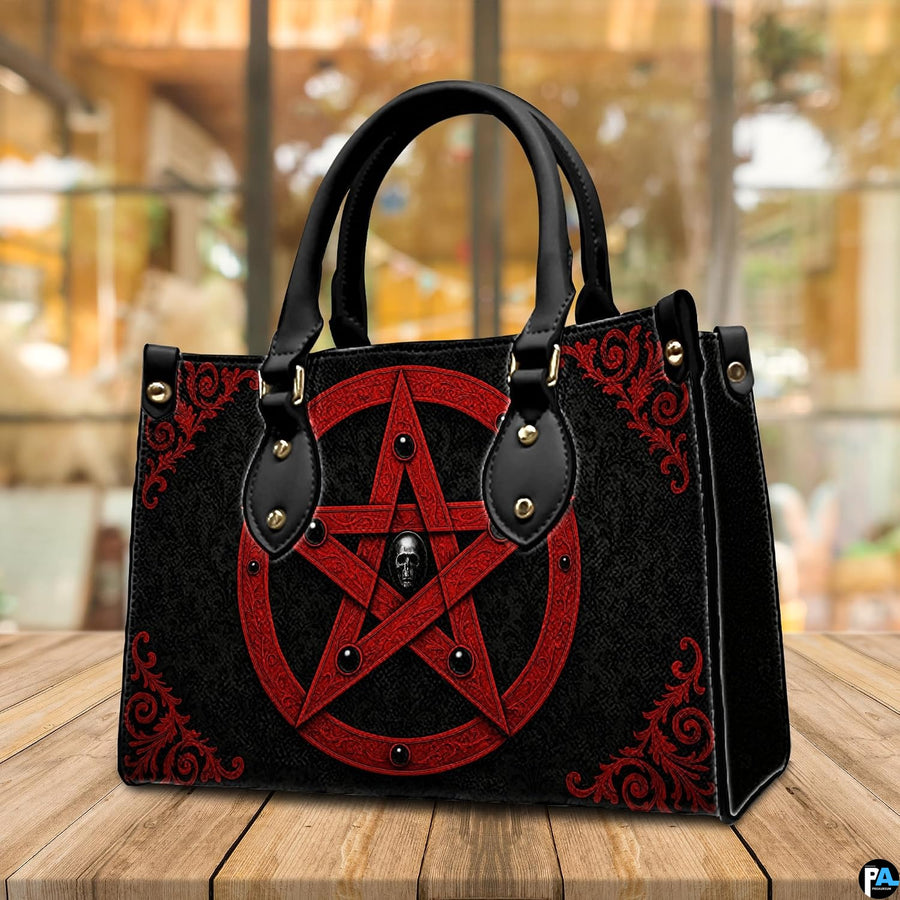 Crimson pentagram handbag displayed on wooden tabletop in front of sunlit cafe window.