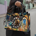 Woman carrying Celestial Lion Satchel Handbag outdoors by top handle on a city walkway.