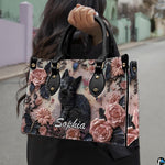 Perspective view of black kitten rose relief handbag and wallet pair