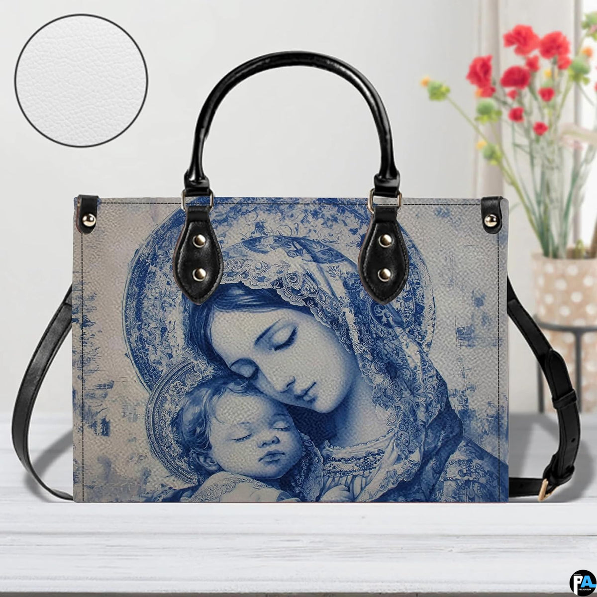 Devotional blue Madonna and Child handbag displayed on white table with background vase