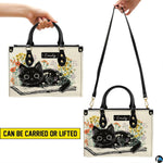 Side perspective view of literary black kitten handbag and wallet showing structured profile