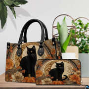 Black cat pumpkin art resting beside green potted plants on a polished wooden surface.