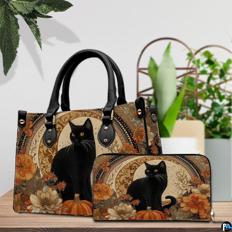 Black cat pumpkin art resting beside green potted plants on a polished wooden surface.