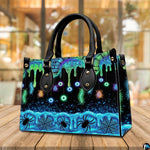 Neon eyeball handbag carried outdoors by top handle on residential street.