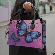 Side profile of blue butterfly handbag showing structured silhouette and black carrying handles.