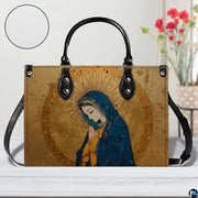 Studio staging of gilded Virgin Mary handbag with texture inset circle and floral backdrop.