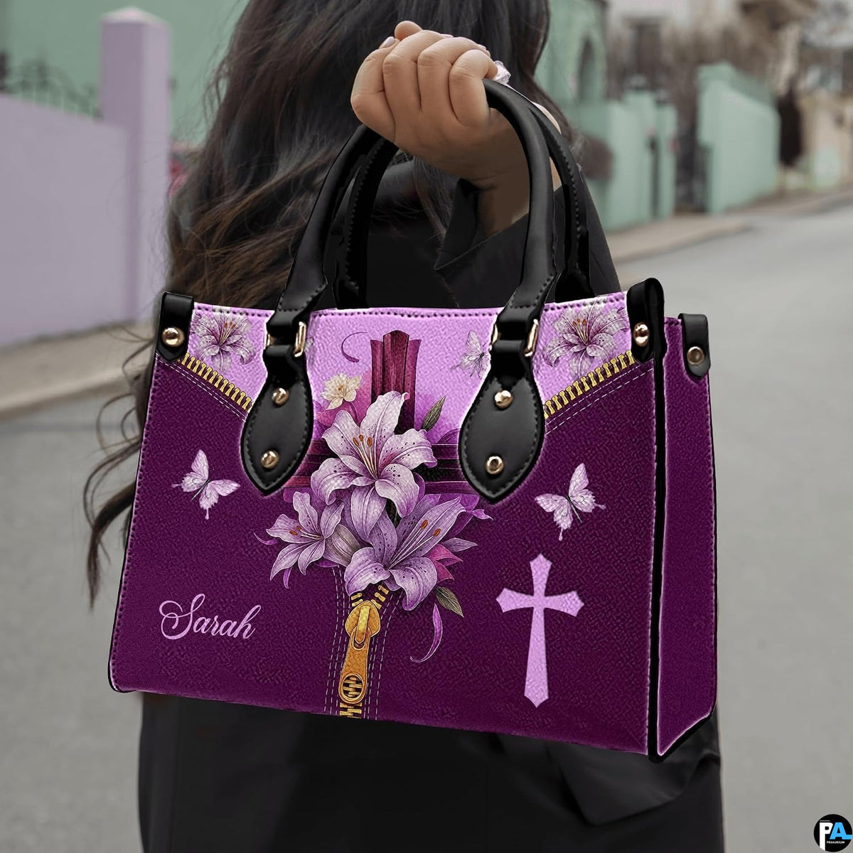 Christian cross Easter lily violet handbag held by top handle while walking outdoors along a street.