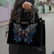 Street lifestyle view of ornate floral butterfly handbag held by hand on urban sidewalk