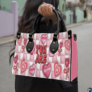 Lifestyle view showing handheld carry of pink affirmation handbag outdoors.