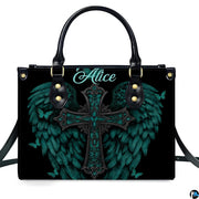 Angled perspective view of turquoise angel wings cross handbag highlighting feathered details.