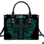 Angled perspective view of turquoise angel wings cross handbag highlighting feathered details.