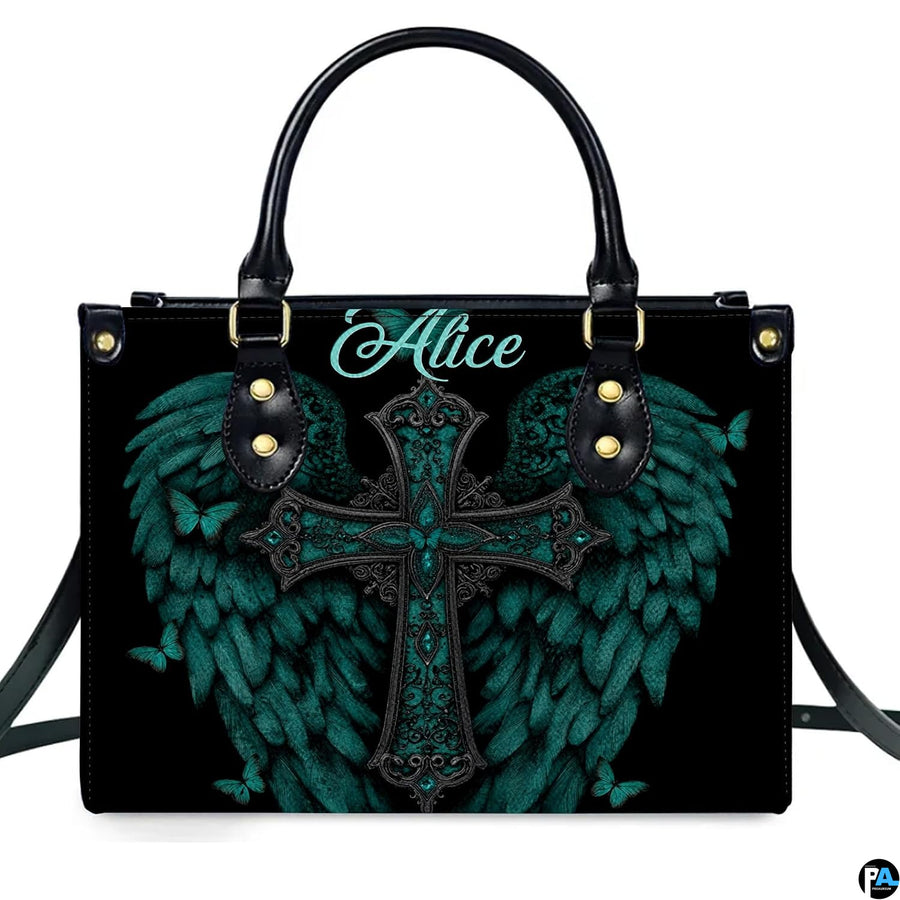 Angled perspective view of turquoise angel wings cross handbag highlighting feathered details.