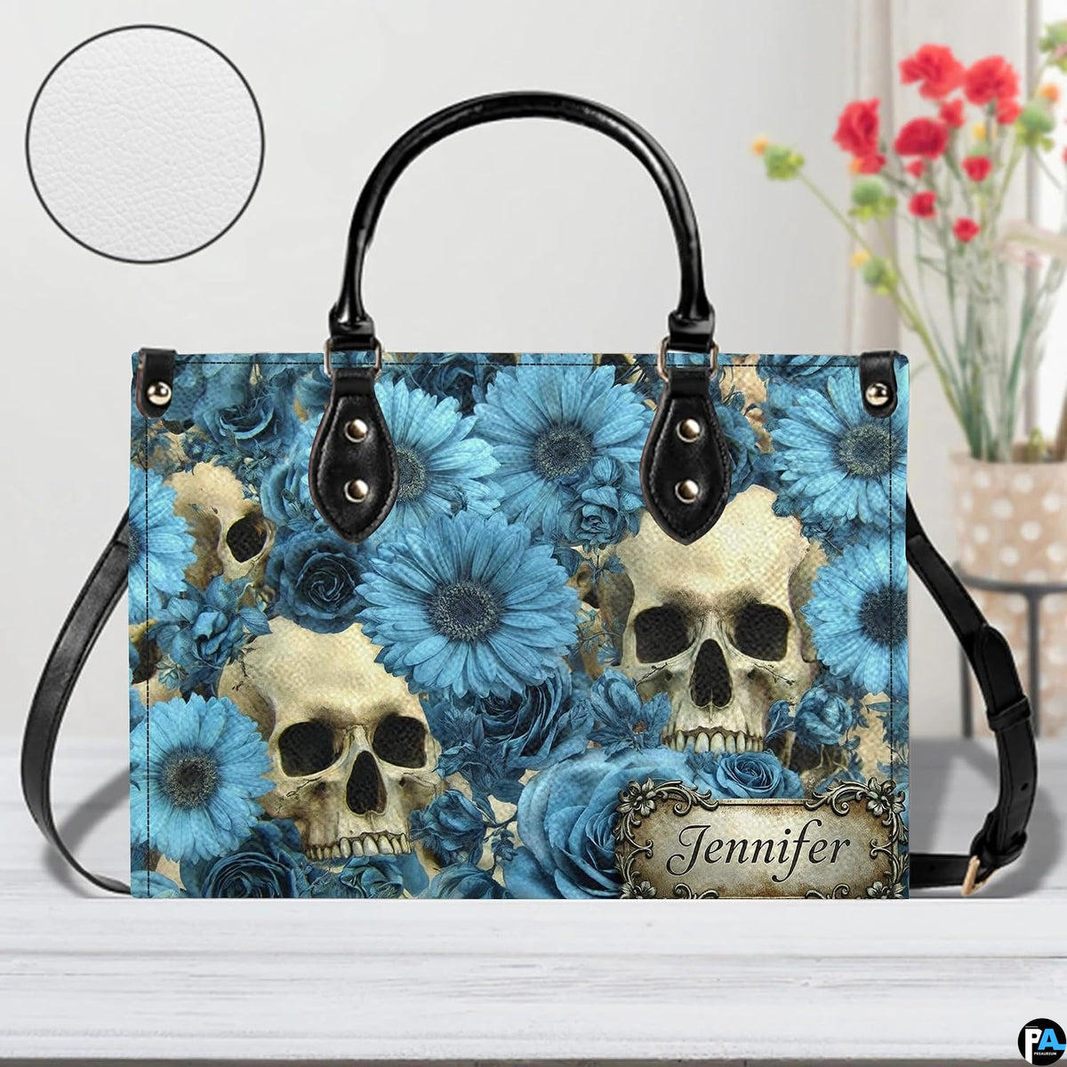 Skull floral daisy handbag on white wooden table beside floral vase with texture swatch inset.