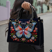 Woman carrying the navy embroidered butterfly handbag outdoors on a city sidewalk.