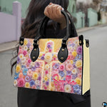 Pastel floral cross handbag carried outdoors by top handles displaying the radiant floral cross artwork.