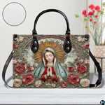 Tabletop lifestyle display of Our Lady of Guadalupe handbag beside floral bouquet.