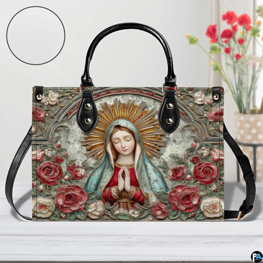 Tabletop lifestyle display of Our Lady of Guadalupe handbag beside floral bouquet.