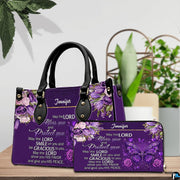 Christian blessing violet handbag and matching wallet set on wooden table near houseplant.