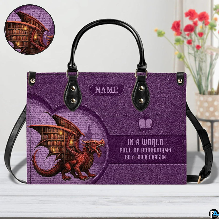 Book dragon violet handbag on white wooden table beside floral vase with detail inset.
