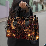 Gothic autumn witch handbag carried outdoors by top handle on residential street.
