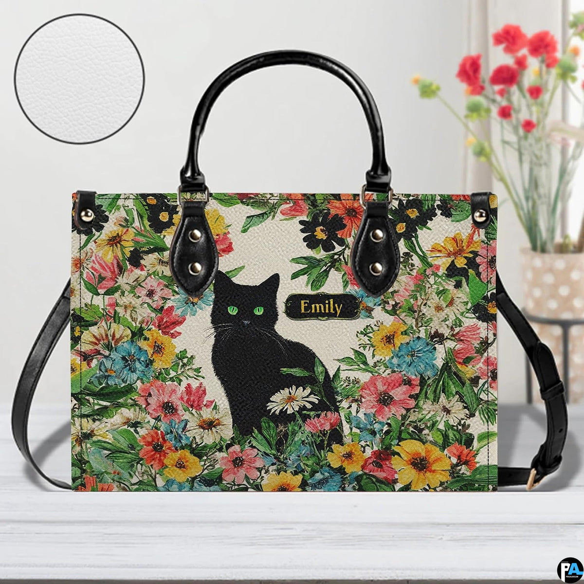 Close-up front view of green-eyed black cat and colorful garden florals on structured tote handbag