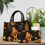 Black woman butterfly art print placed on wooden tabletop beside green houseplant leaves.