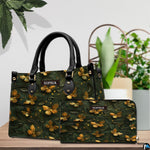Top-handle handbag and matching wallet shown together on a tabletop beside house plants.