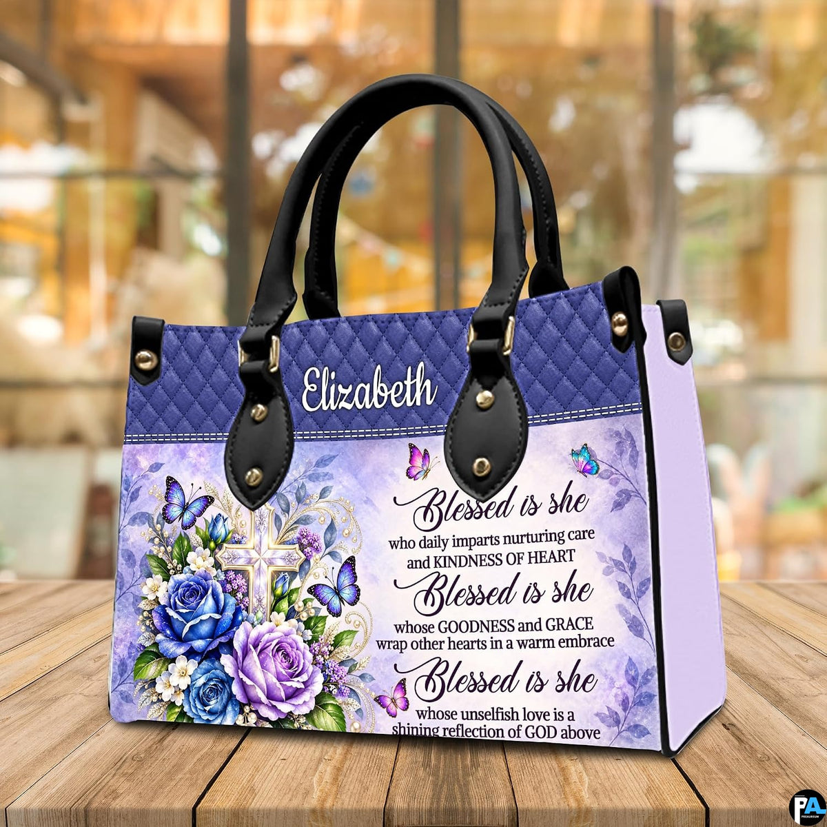 Floral cross handbag displayed on wooden tabletop in front of sunlit cafe window.
