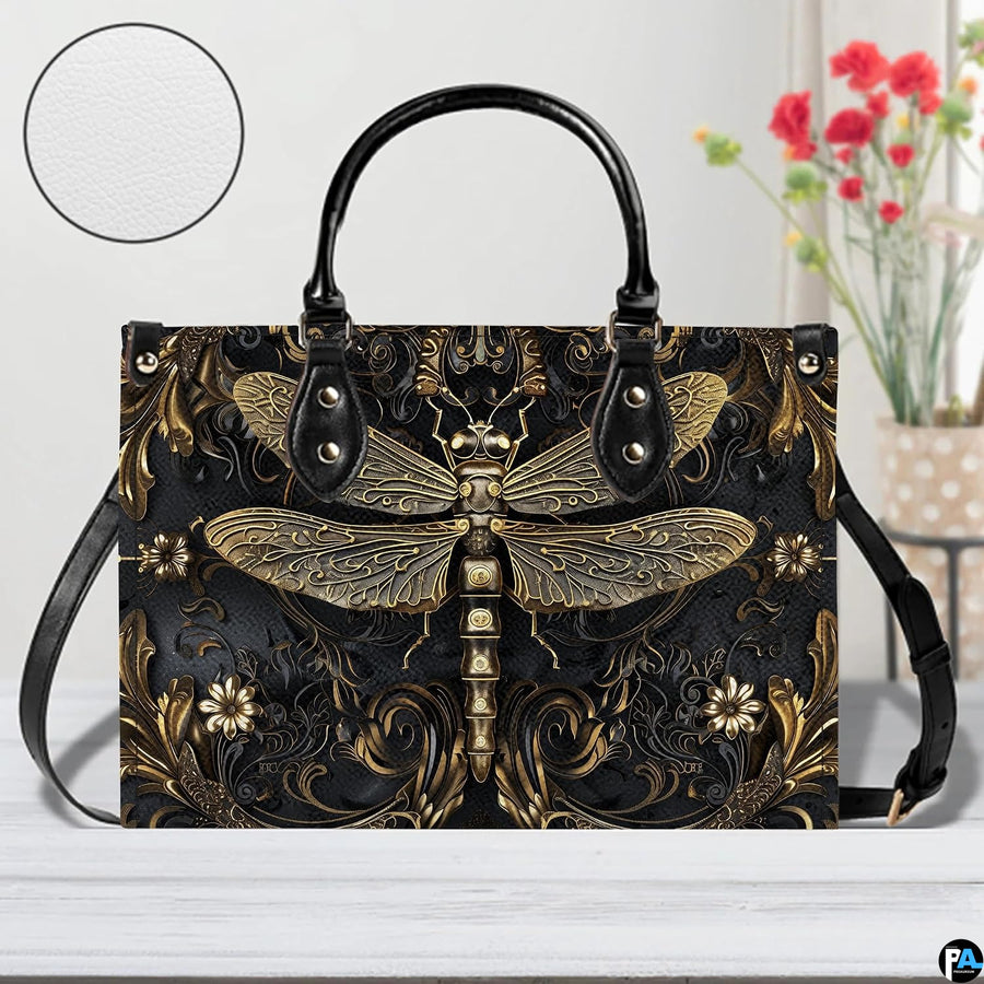 Front view of gold dragonfly handbag on white table with floral vase and texture swatch inset