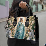 Lifestyle display of Our Lady of the Rosary handbag carried by model showing artwork and scale