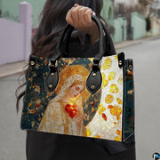 Model carrying stained glass mosaic Virgin Mary handbag outdoors on street.