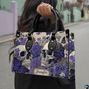Violet skull handbag carried outdoors by top handle along residential street.