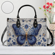 Tabletop cafe view of Delftware floral butterfly handbag standing on wooden surface