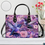 Detailed view of teal and violet hummingbird wings amidst purple garden flora on handbag.