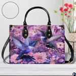 Detailed view of teal and violet hummingbird wings amidst purple garden flora on handbag.