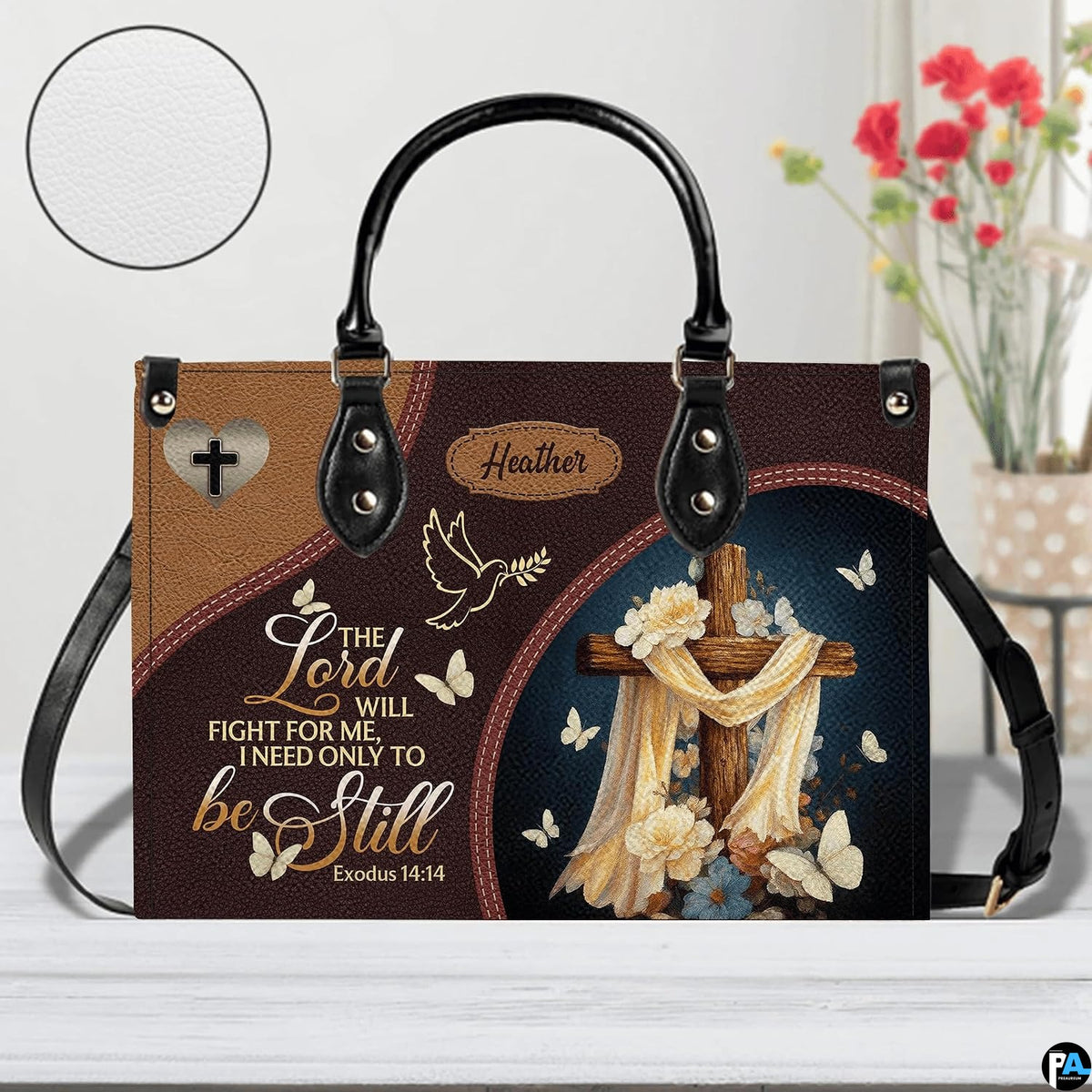 Christian wooden cross handbag displayed on white table beside floral bouquet.