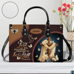 Christian wooden cross handbag displayed on white table beside floral bouquet.