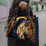 Lifestyle demonstration of the praying Madonna stained glass handbag held outdoors