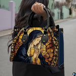 Lifestyle demonstration of the praying Madonna stained glass handbag held outdoors