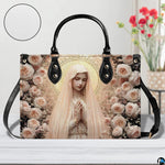 Blush rose Marian handbag shown on white wooden table with texture swatch and background floral vase.