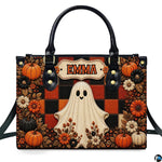 Front view of autumn satchel displaying cute smiling ghost on orange and black plaid grid with pumpkins.