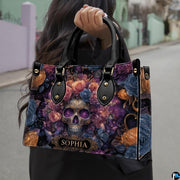 Cosmic skull floral handbag carried outdoors by top handle along residential street.