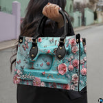 Model outdoors holding turquoise sewing machine artwork accessory in natural daylight.