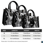 Gothic black cat handbag displayed on white table beside floral bouquet.