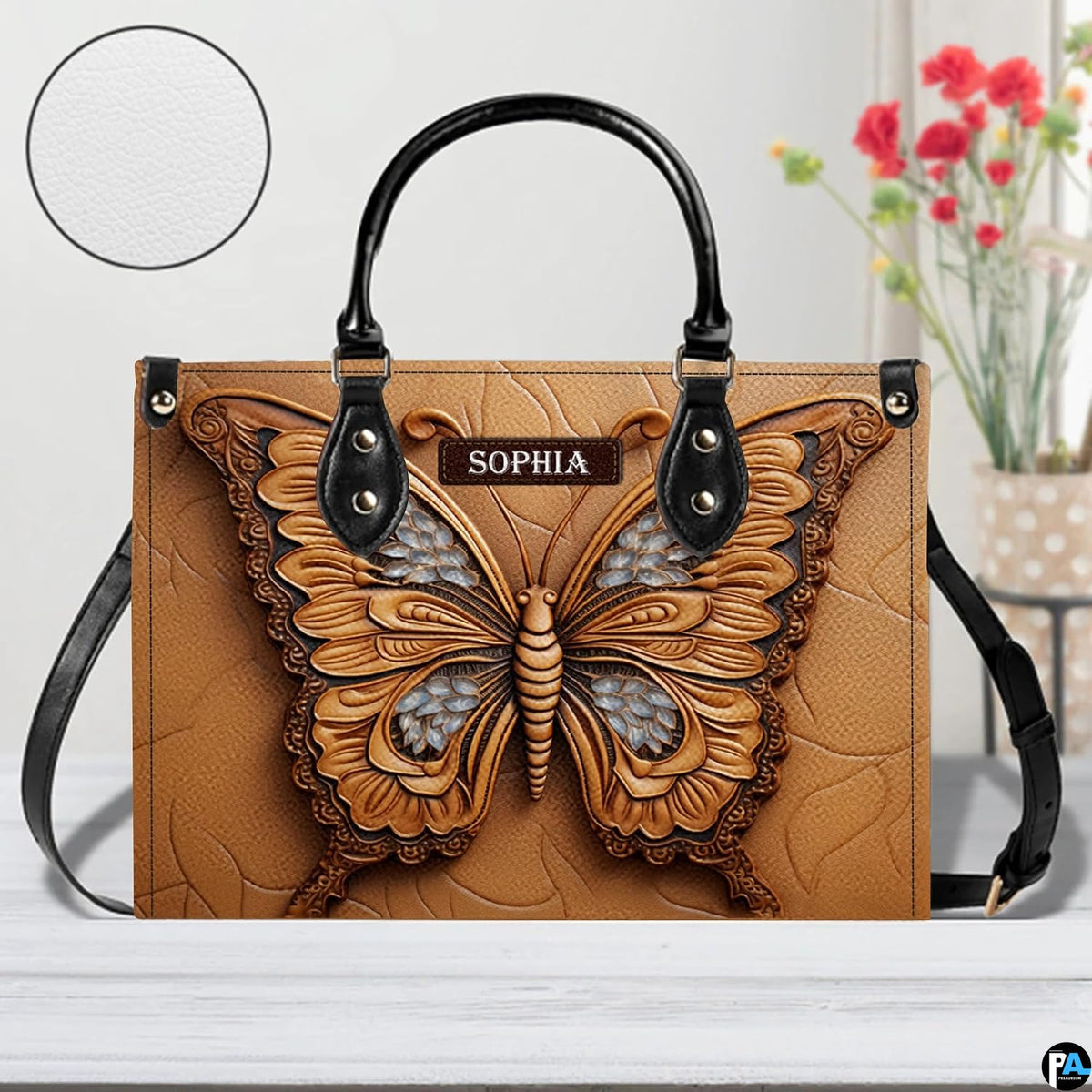 Artisan butterfly handbag showcased on a white tabletop beside a floral arrangement and texture circular swatch.