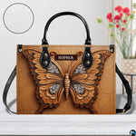 Artisan butterfly handbag showcased on a white tabletop beside a floral arrangement and texture circular swatch.