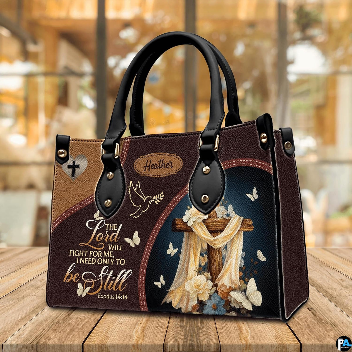 Christian wooden cross handbag displayed on wooden tabletop in front of sunlit windows.